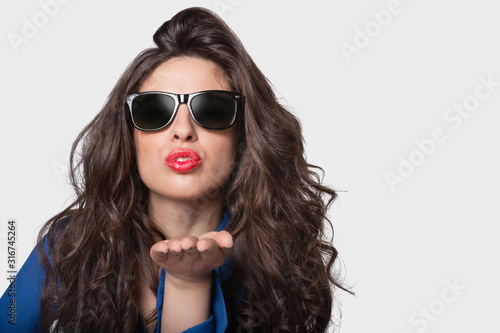 Wallpaper Mural Portrait of a young woman in sunglasses blowing a kiss over gray background Torontodigital.ca