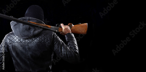 Man with shotgun on dark background.
