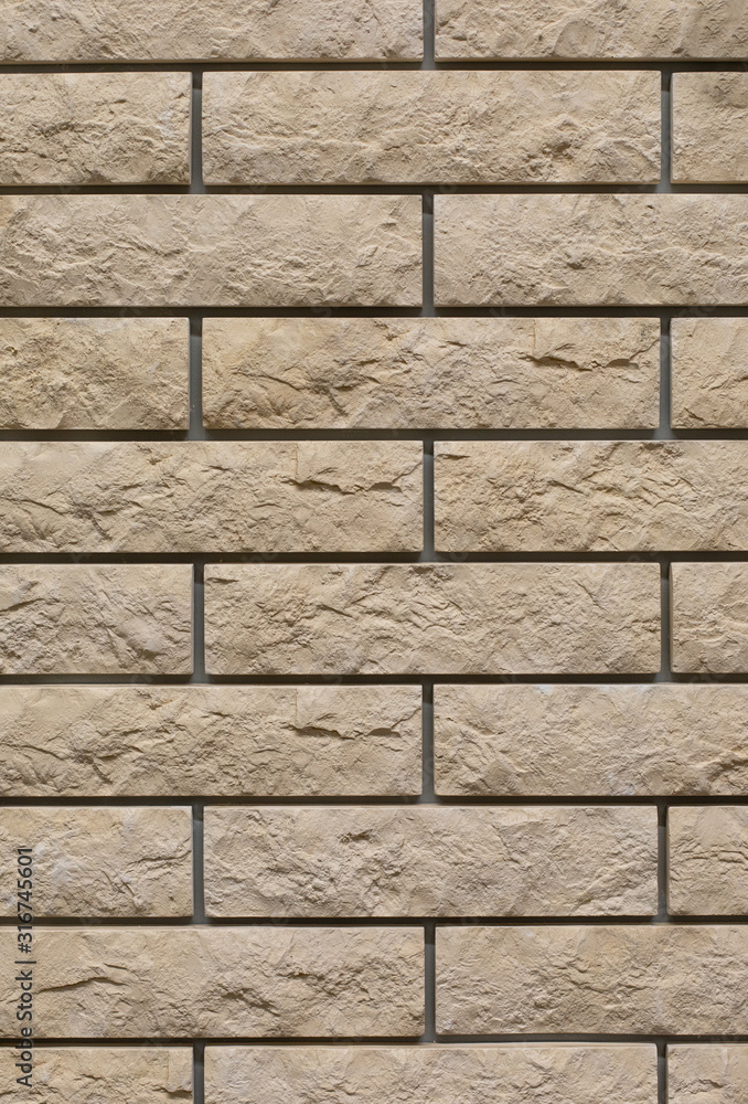 Obraz premium Brick wall with uneven rough beige brick. Decorative wall decoration with brick stone, texture background backdrop. Wall of smooth brick textured effect