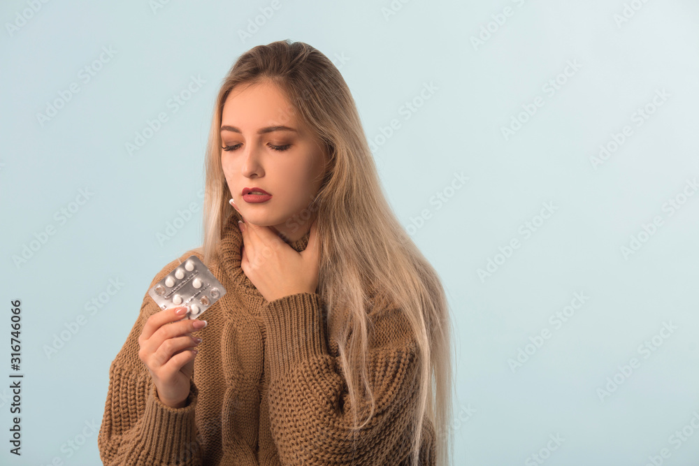 sad beautiful woman in a sweater on a blue background with pills in hands sad beautiful woman in a sweater on a blue background with pills in hands