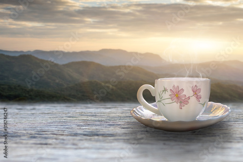 A cup of hot espresso coffee mugs placed with cookies on a wooden floor with morning fog and moutains with sunlight background,coffee morning
