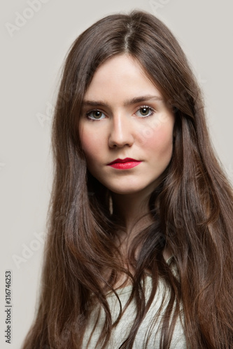 Portrait of sensuous young woman with red lips against gray background