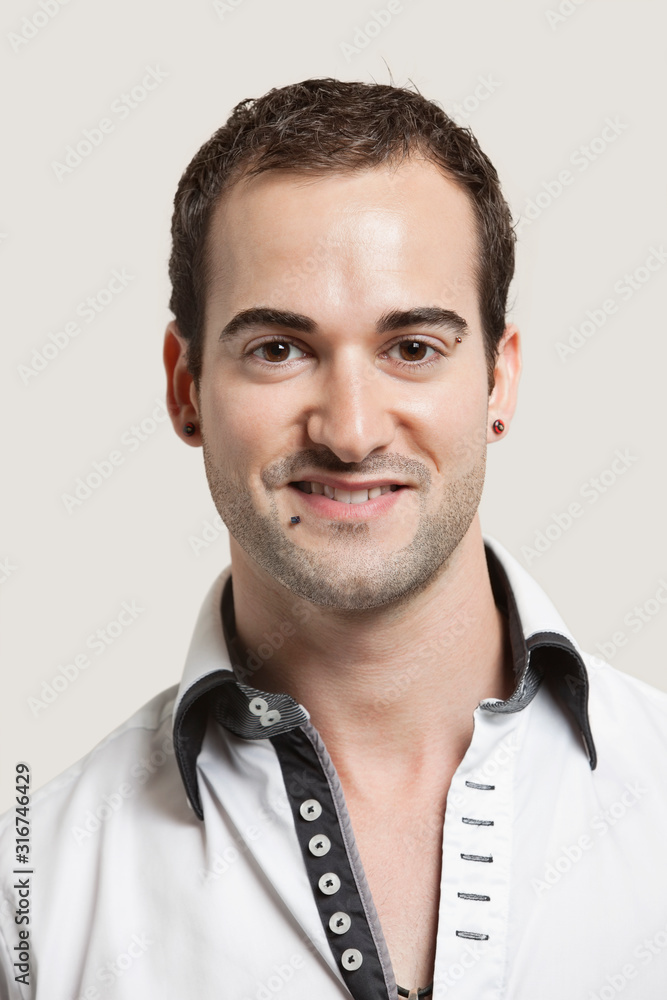 Close-up portrait of young man smiling over gray background Close-up portrait of young man smiling over gray background