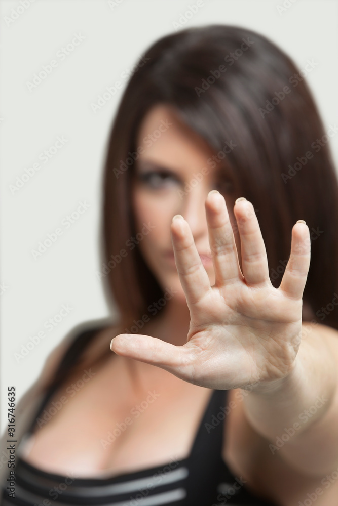 Portrait of a young woman gesturing stop sign over gray background Portrait of a young woman gesturing stop sign over gray background