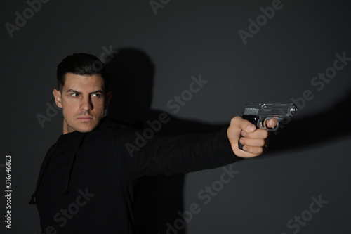 Professional killer with gun on black background