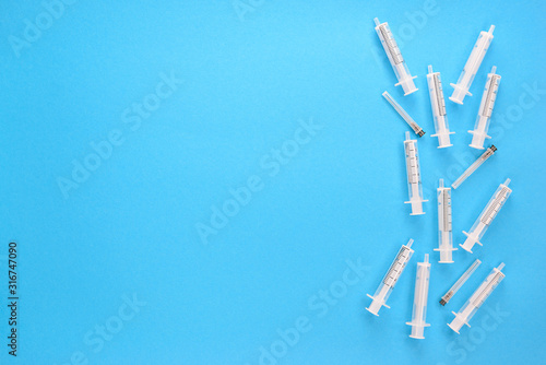 Medical syringes with needles on a blue background. Horizontal orientation  top view  copy space.