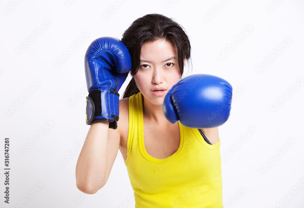 Portrait of young Asian woman wearing blue boxing gloves against white background Portrait of young Asian woman wearing blue boxing gloves against white background
