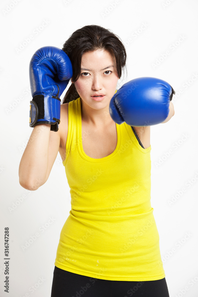 Portrait of young Asian woman wearing boxing gloves against white background Portrait of young Asian woman wearing boxing gloves against white background