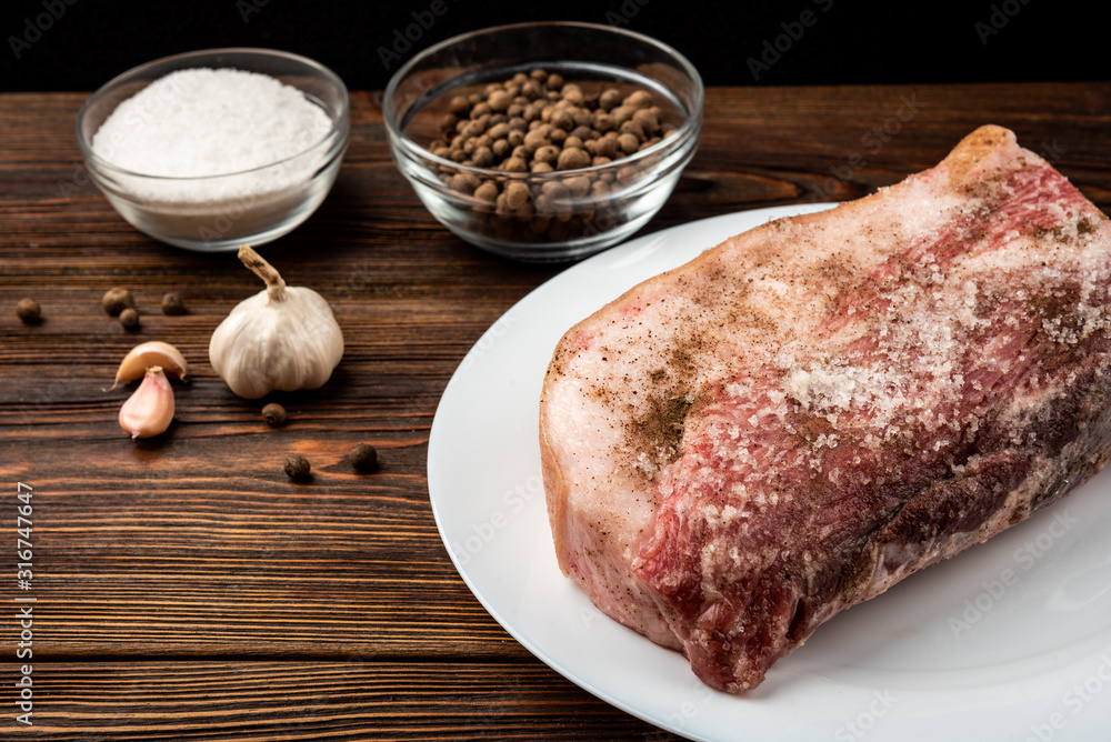 Pork meat with spices on dark wooden background.