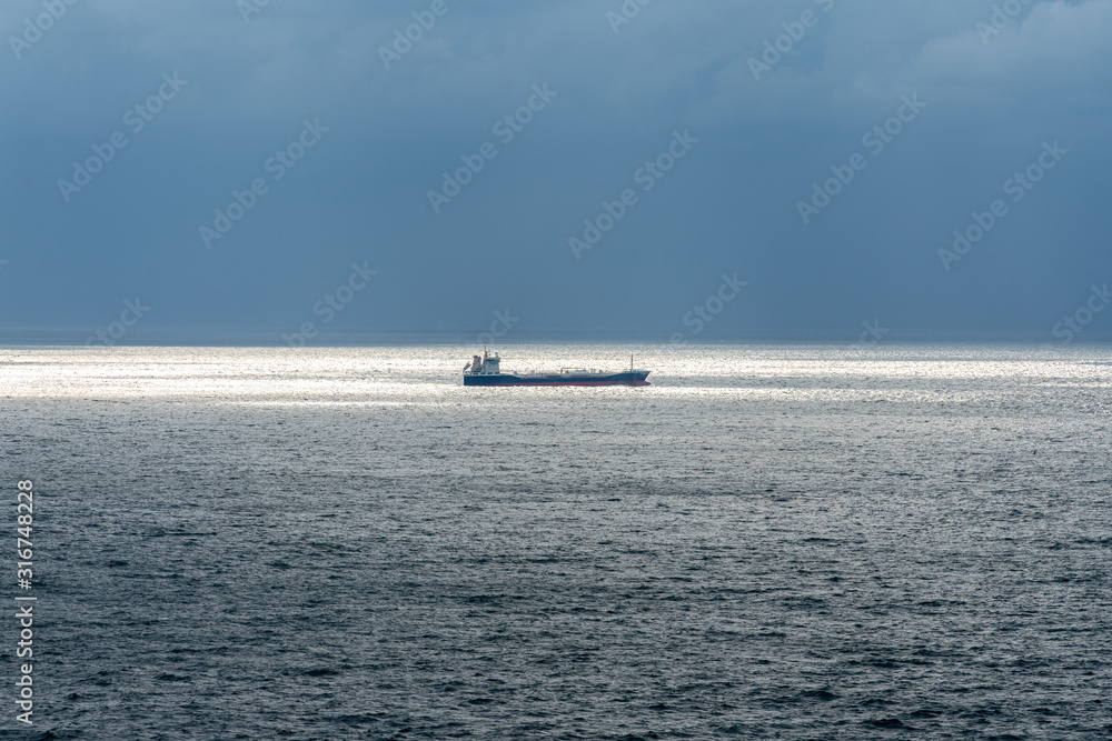 Cargo ship in sunlight with incoming stormy weather