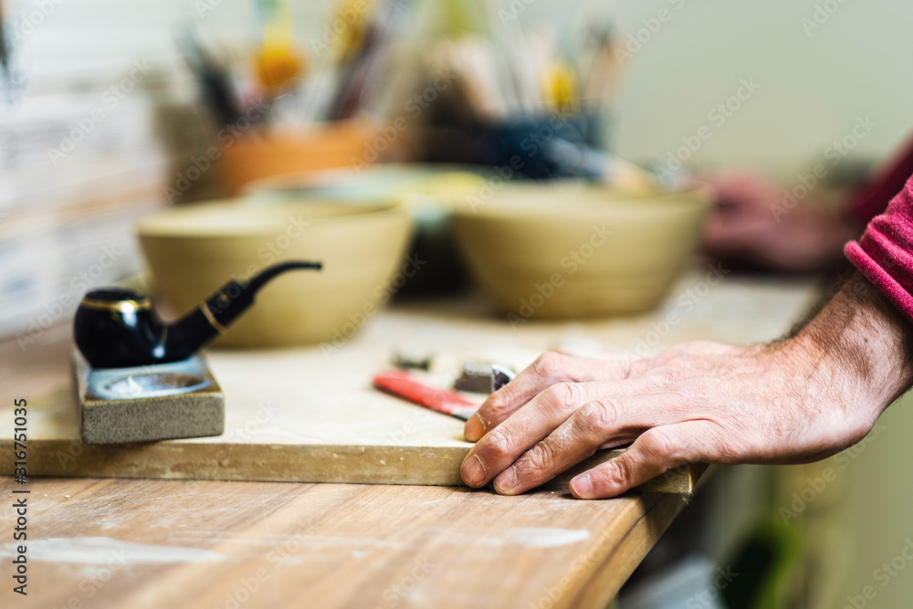 Potter checking tools on pottery studio table, hands detail, shallow debt of field, small art business concept Potter checking tools on pottery studio table, hands detail, shallow debt of field, small art business concept