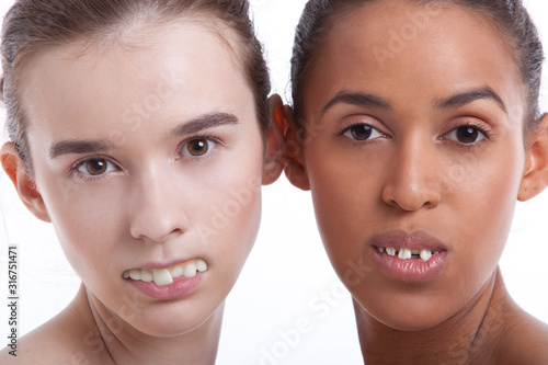 Portrait of two young women with fake teeth against white background