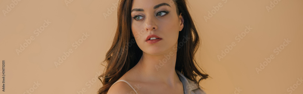 Obraz premium Panoramic shot of beautiful girl in bra and coat looking away isolated on beige