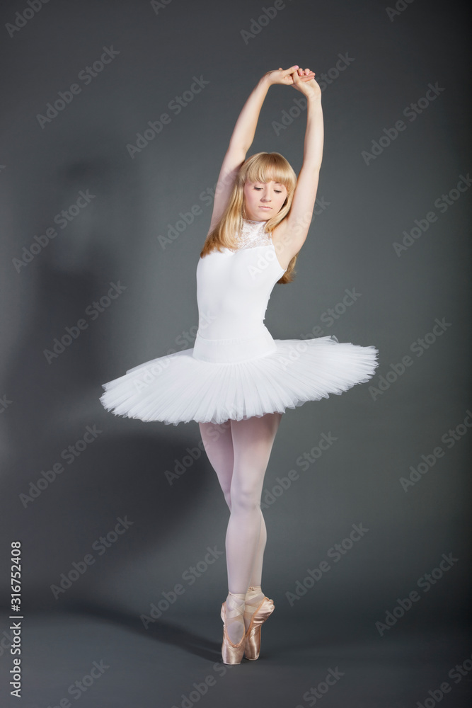 Naklejka premium Young female ballet dancer tiptoeing over grey background