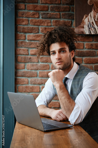 Attractive bearded young man working on laptop while sitting in 