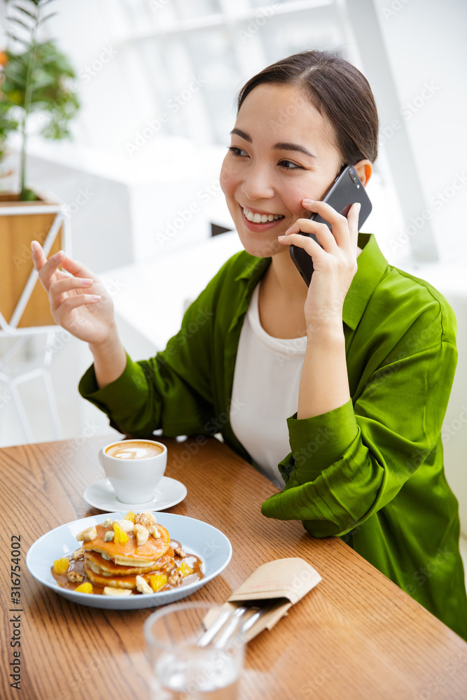 Smiling asian woman having pancakes for breakfast Smiling asian woman having pancakes for breakfast