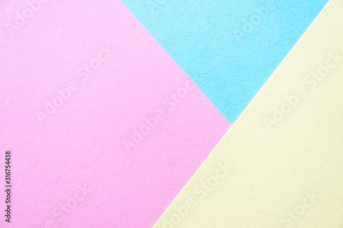 Lilac, soft pastel yellow and blue colored textured paper for the background. Geometric empty paper background of three tones for copy space.