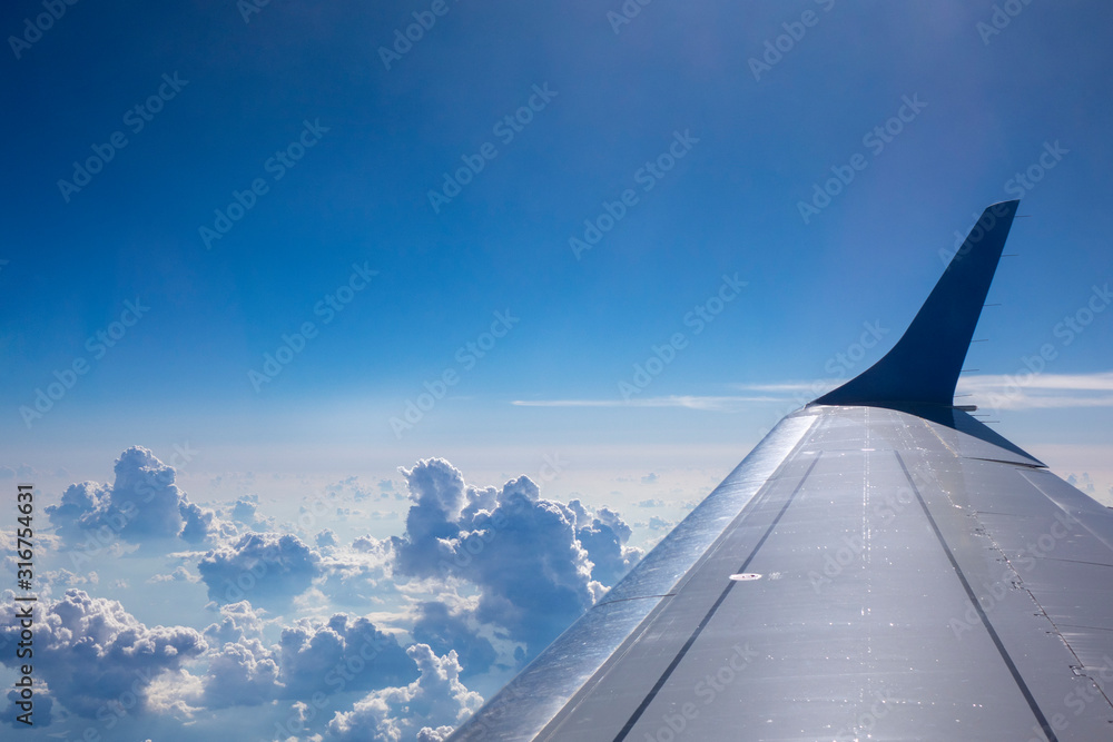Plane wing on a blue sky cloudy background