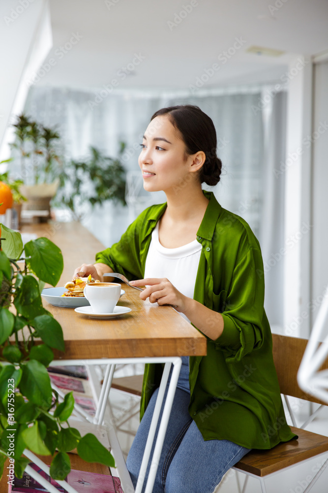 Smiling asian woman having pancakes for breakfast Smiling asian woman having pancakes for breakfast