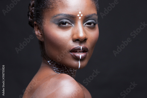 Portrait of young beautiful black woman posing with traditiional paint  photo