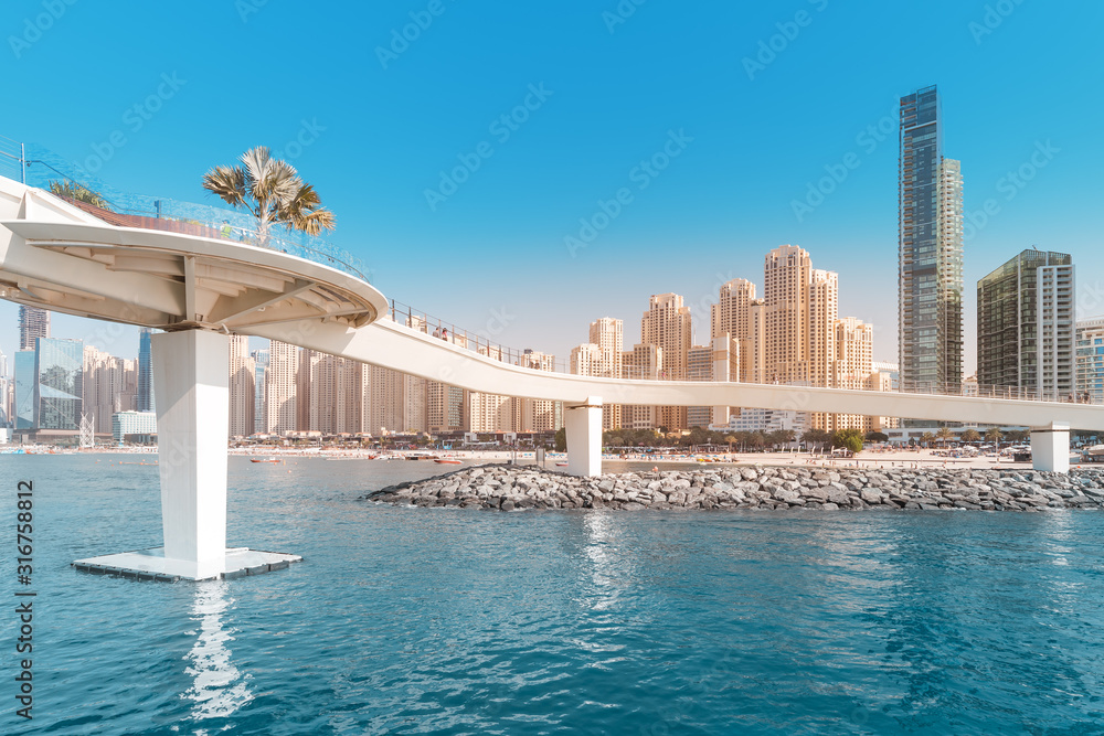 Pedestrian Footbridge at the Dubai Marina harbor with various residential buildings at the background