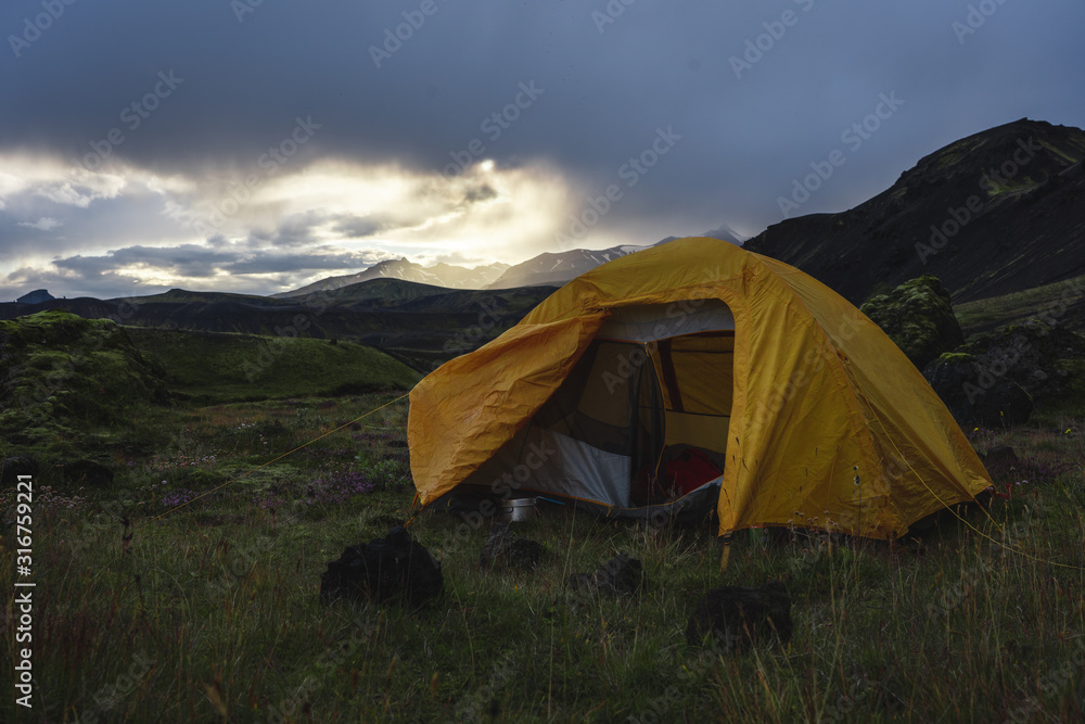 Open yellow camping tent in an open moss field during sunset. Shot on adventure in Icelandic highlands