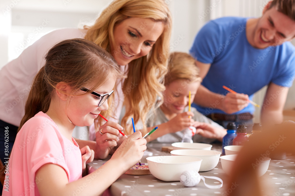 Parents With Children Sitting At Table Decorating Eggs For Easter At Home Parents With Children Sitting At Table Decorating Eggs For Easter At Home