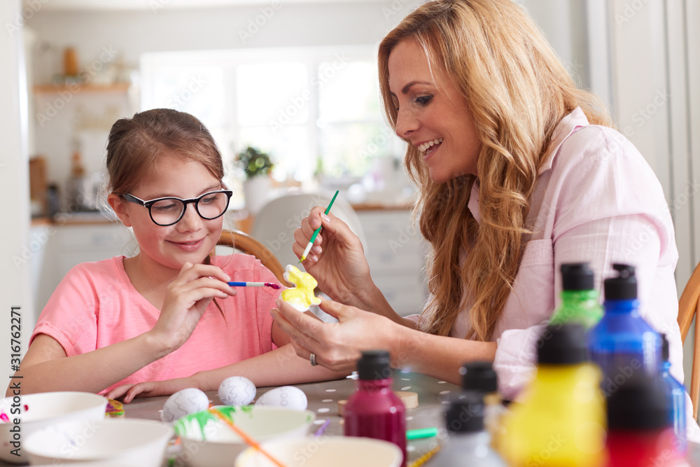 Mother With Daughter Sitting At Table Decorating Eggs For Easter At Home Mother With Daughter Sitting At Table Decorating Eggs For Easter At Home