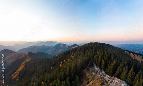 Aerial view of the Recreation Mountain Pysany kamin in Carpathian mountains. autumn. Pine forest, houses on the peaks, yellow fields and trees. Mountain meadow. sunset, Ukraine