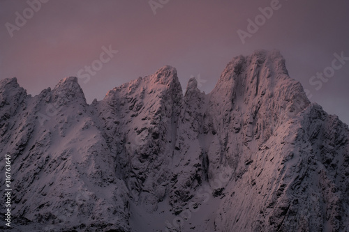 sunrise at lofoten islands mountains. peaks during winter sunrise. pinky and red light with peak and mountains under snow. skottinden and himmeltindan photo