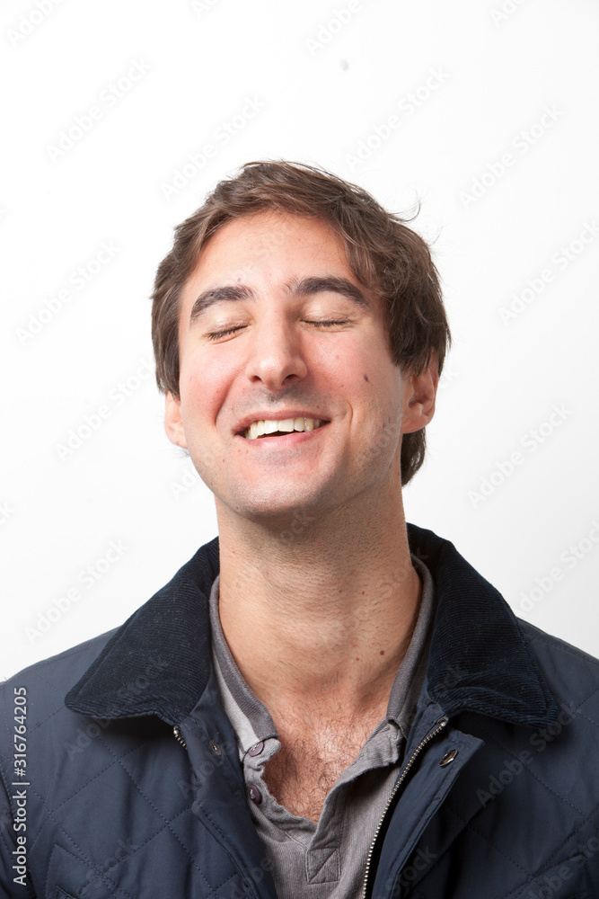 Close-up of young man with eyes closed smiling against white background Close-up of young man with eyes closed smiling against white background