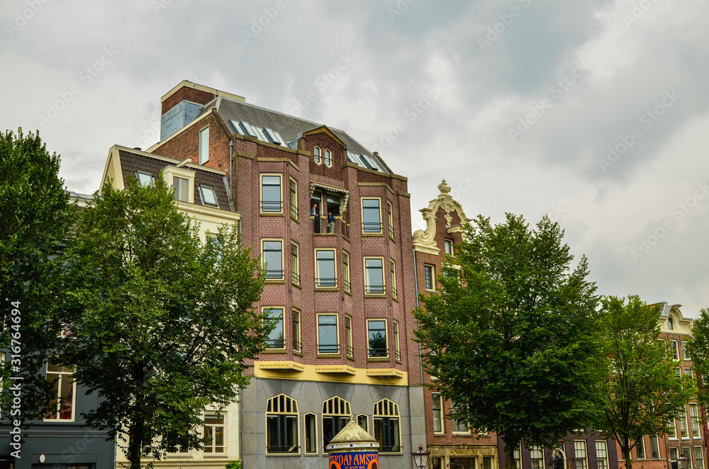 Amsterdam, Holland, August 2019. The typical and charming houses: they are a symbol of the city represented on a postcard. With brightly colored brick facades and distinctive roofs.