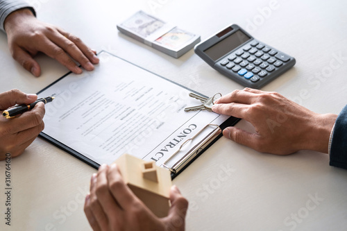 Real estate agent are presenting home loan and sending keys to customer after signing contract to buy house with approved property application form, Insurance Home concept