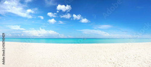 Beautiful beach with white sand, turquoise ocean and blue sky with clouds in sunny day. Panoramic view. Natural background for summer vacation.