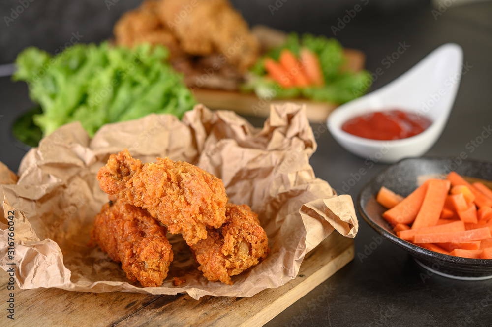 Crispy fried chicken on a cutting board with tomato sauce and carrot, Selective focus. Crispy fried chicken on a cutting board with tomato sauce and carrot, Selective focus.