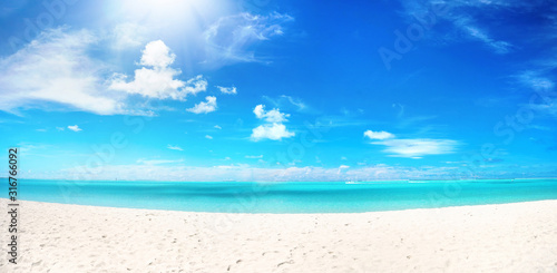 Fototapeta Naklejka Na Ścianę i Meble -  Beautiful beach with white sand, turquoise ocean water and blue sky with clouds in sunny day. Panoramic view. Natural background for summer vacation.