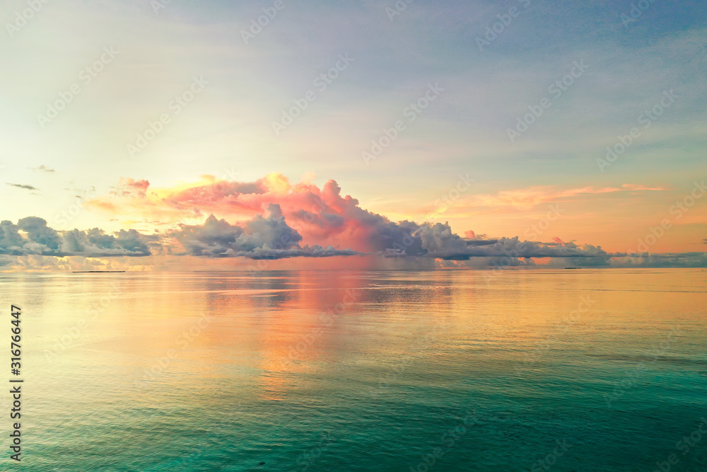 Beautiful cloud over ocean water at sunset in Golden pink blue and green tones. Colorful natural landscape, copy space.