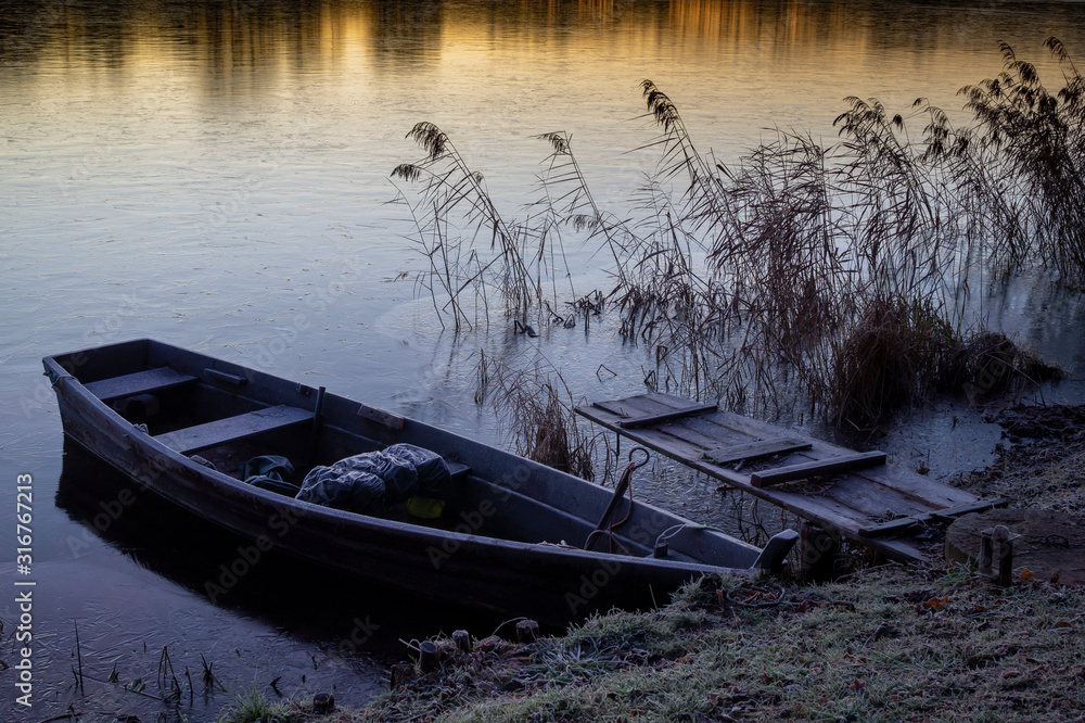 Wooden boat moored on a tranquil frozen lake Wooden boat moored on a tranquil frozen lake