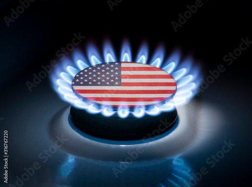 Burning gas burner of a home stove in the middle of which is the flag of the country of USA. Gas import and export delivery concept, price per cubic meter, transit, background photo