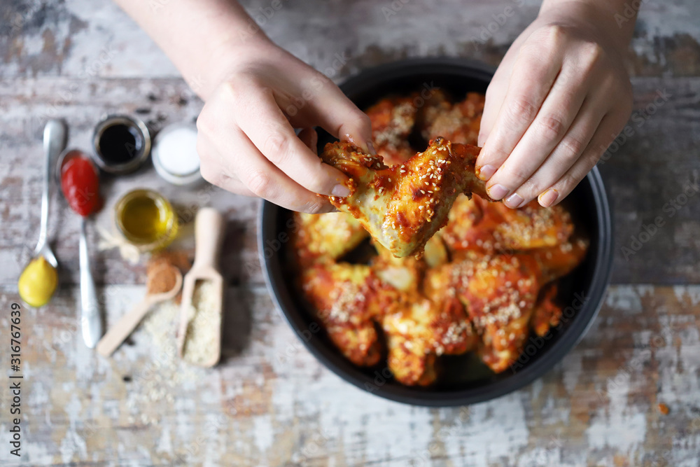 Selective focus. A man eats chicken wings with his hands. Chicken wings baked with sesame seeds. Buffalo Wings.