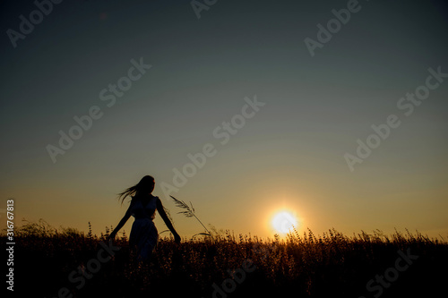 back view of a woman in a dress in lavender field in the sunset
