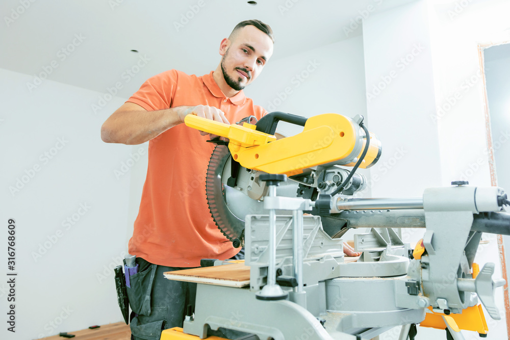 Handwerker schneidet Holzdiele mit der Kappsäge Handwerker schneidet Holzdiele mit der Kappsäge
