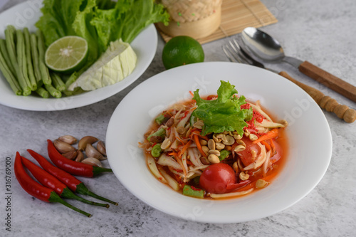 Thai papaya salad in a white plate with chili, lime, and garlic.