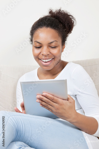 Happy young African American woman using tablet PC