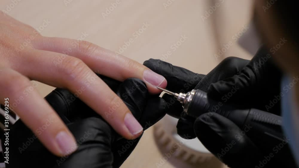 Woman in black rubber gloves making manicure. Nail manicure process in a beauty salon. Manicure in the salon. Woman in black rubber gloves making manicure. Nail manicure process in a beauty salon. Manicure in the salon.