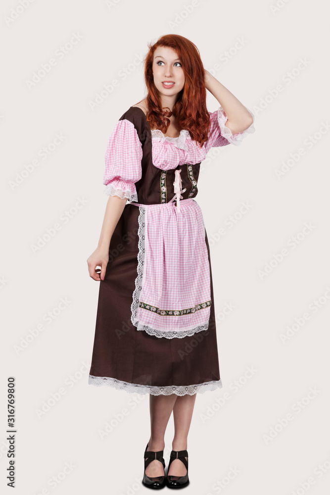 Young confused woman in maid costume standing against gray background Young confused woman in maid costume standing against gray background