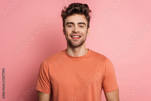 handsome, happy man smiling at camera on pink background