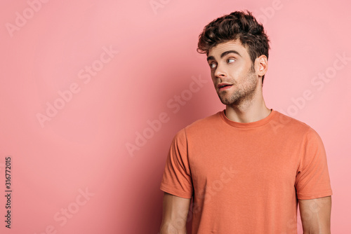 handsome, dreamy man looking away on pink background