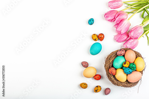 Stylish background with colorful quail, easter eggs with copy space for text. Next lying fresh pink tulip flowers. isolated on white background. Flat lay, top view, mockup, overhead, template