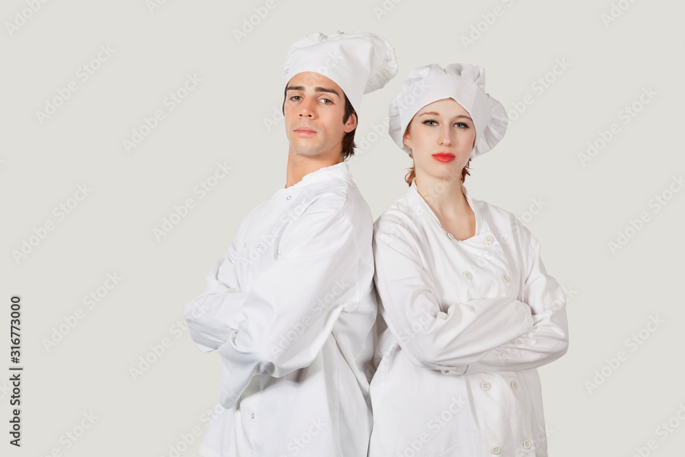 Portrait of two confident chefs with arms crossed against gray background